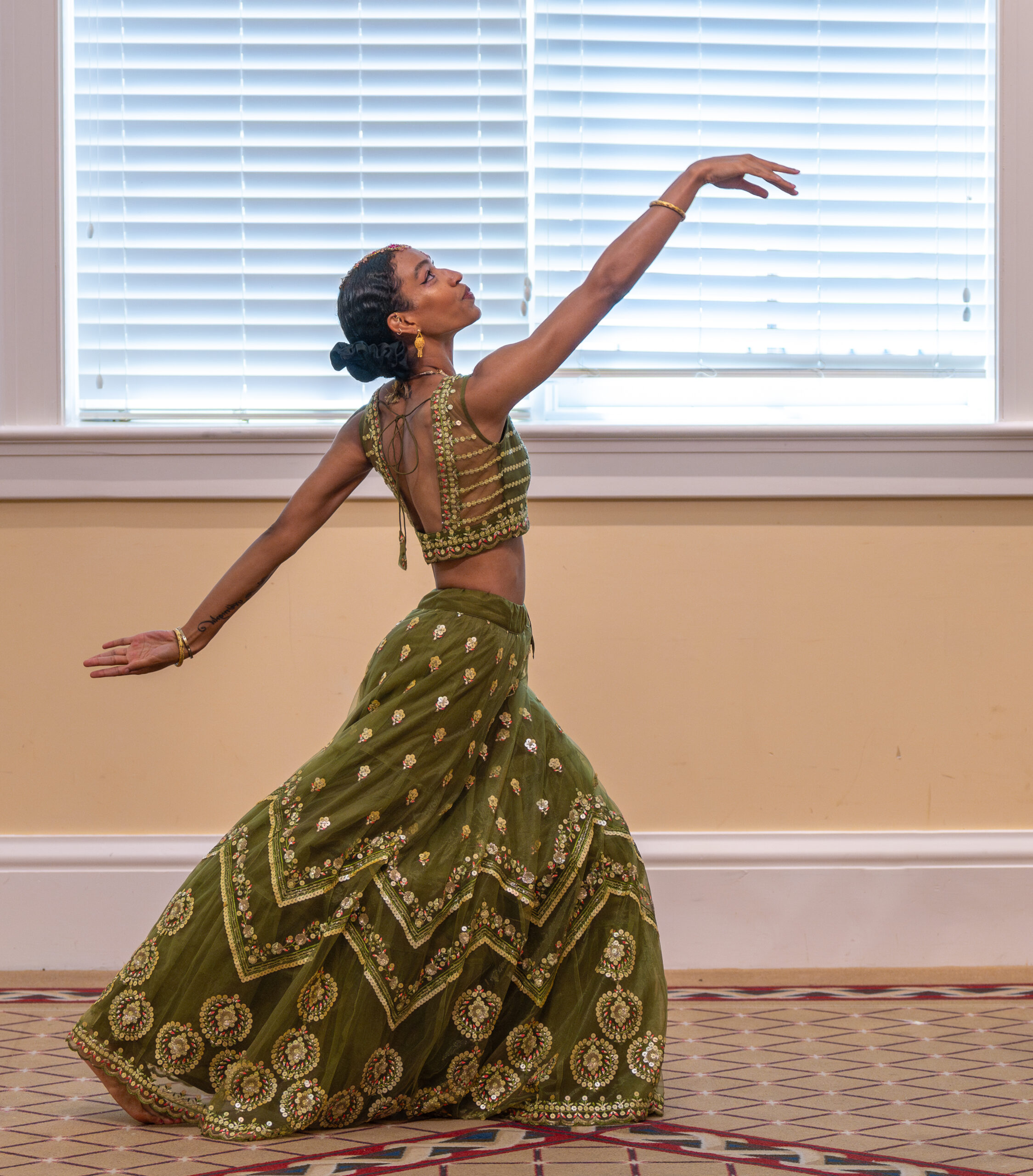 Young woman dancer in green in elongated pose.