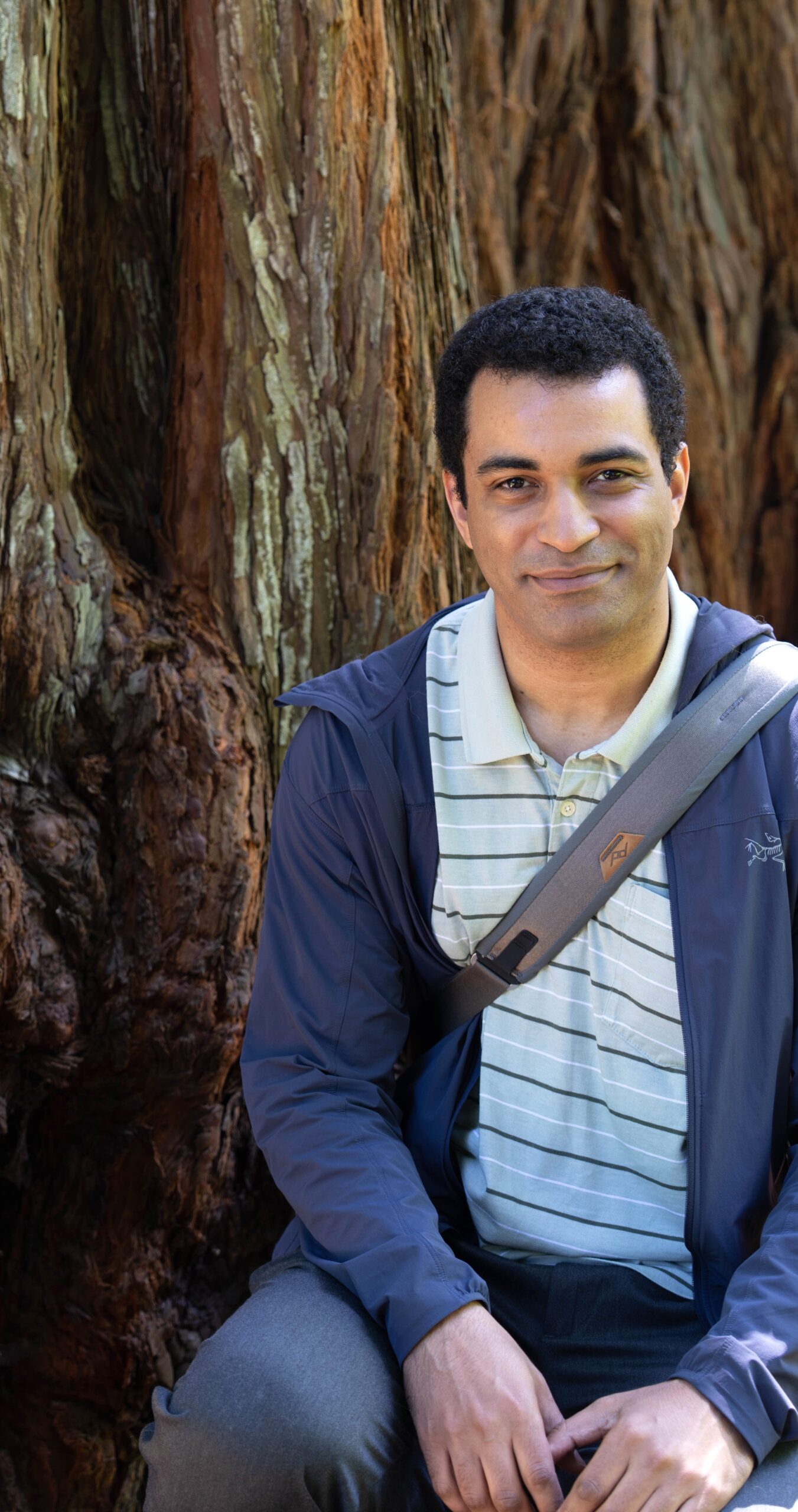 Young man in front of redwood tree.