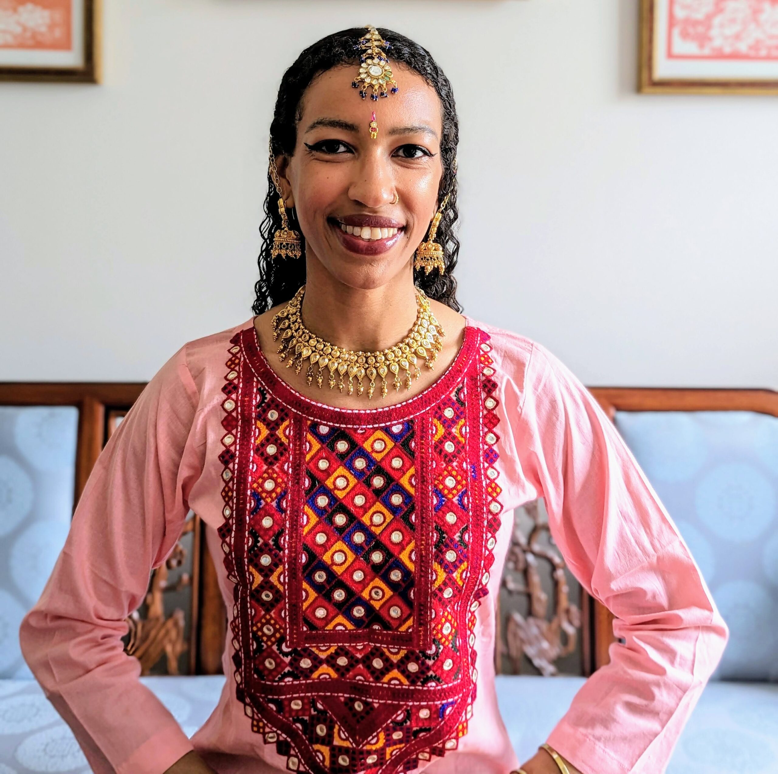 Tasherit Sturm Dahal in a pink Rajasthani costume posing for a portrait with gold Indian jewelry.
