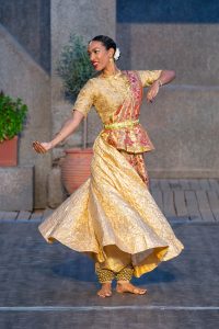 Woman doing Kathak dance in a gold costume
